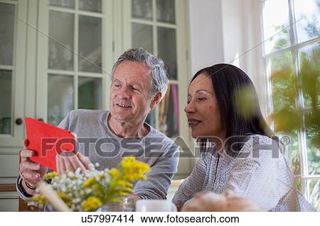 Picture - "Senior couple, sitting at table, looking at digital tablet". Fotosearch