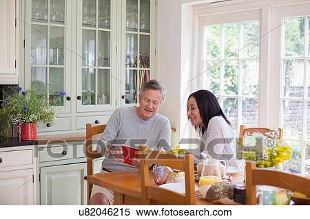 "Senior couple, sitting at table, looking at digital tablet" View Large Photo Image Stock Photography - "Senior couple, sitting at table, looking at digital tablet". Fotosearch