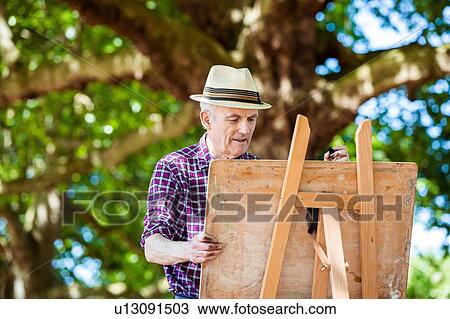 Stock Image - "Senior man drawing in park, Hackney, London". Fotosearch