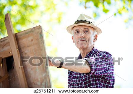 Stock Image - "Senior man drawing in park, Hackney, London". Fotosearch