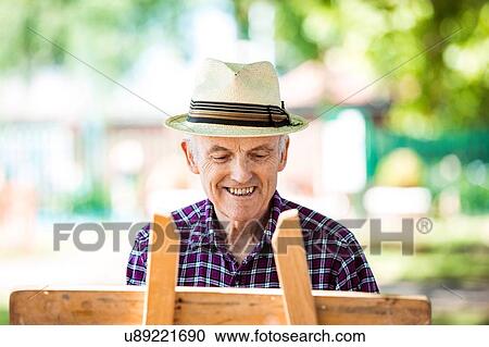 Stock Image - "Senior man drawing in park, Hackney, London". Fotosearch