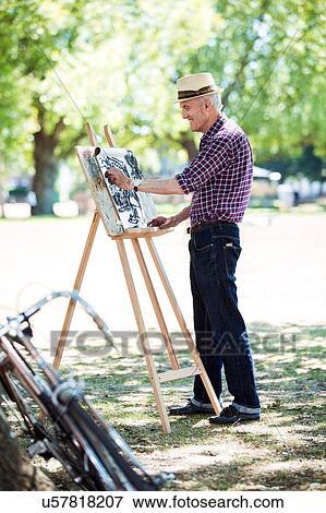Stock Photo - "Senior man drawing in park, Hackney, London". Fotosearch