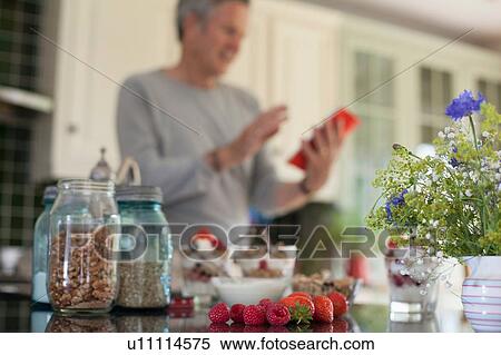 Stock Photography - "Senior man in kitchen, looking at digital tablet". Fotosearch