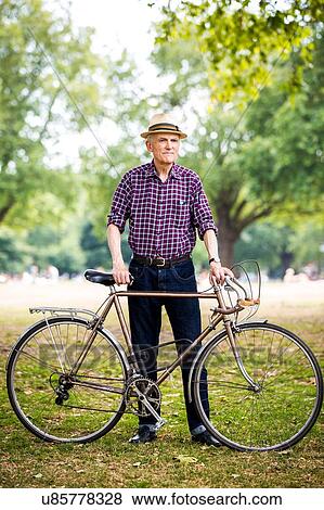Stock Photo - "Senior man with bicycle in park, Hackney, London". Fotosearch