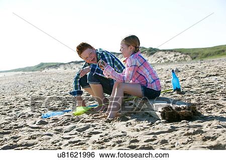 Side view of girl and boy sitting on driftwood talking View Large Photo Image Stock Photograph - Side view of girl and boy sitting on driftwood talking. Fotosearch