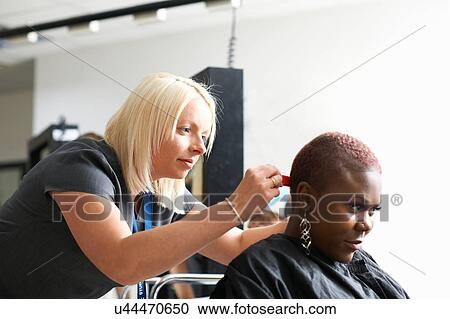 Side view of hairdresser and young woman wearing hair cutting cape in hair salon looking down View Large Photo Image Stock Image - Side view of hairdresser and young woman wearing hair cutting cape in hair salon looking down. Fotosearch