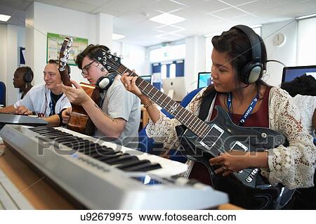 Small group of college students sitting in front of keyboards wearing headphones playing guitars View Large Photo Image Stock Photography - Small group of college students sitting in front of keyboards wearing headphones playing guitars. Fotosearch