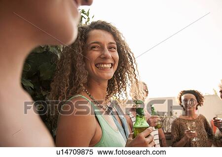 Stock Photography - Small group of friends holding drinks talking and smiling. Fotosearch