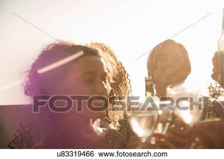 "Small group of friends making a toast smiling, lens flare" View Large Photo Image Stock Photograph - "Small group of friends making a toast smiling, lens flare". Fotosearch