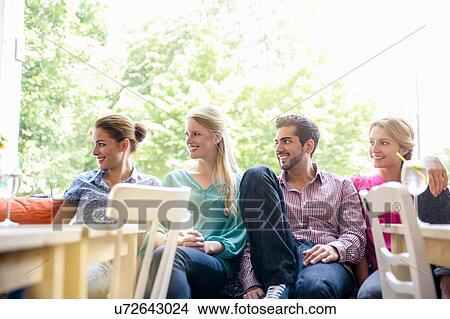 Small group of young adults sitting side by side in window seat looking away smiling View Large Photo Image Picture - Small group of young adults sitting side by side in window seat looking away smiling. Fotosearch