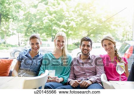 Stock Photograph - Small group of young adults sitting side by side in window seat looking at camera smiling. Fotosearch