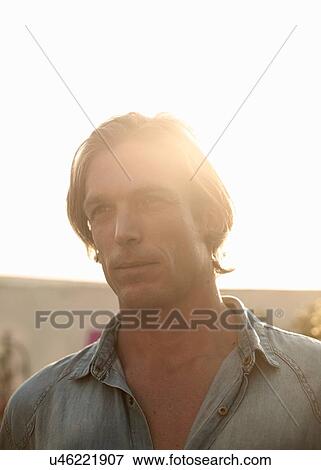 Stock Photo - Sunlit portrait of confident mid adult man. Fotosearch
