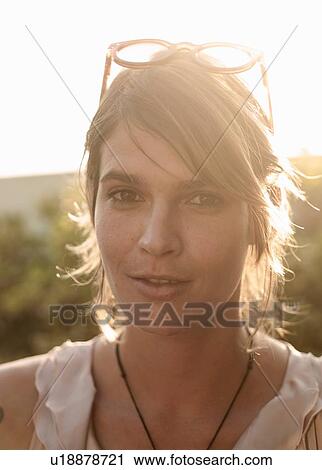 Stock Image - Sunlit portrait of young woman with short blond hair. Fotosearch