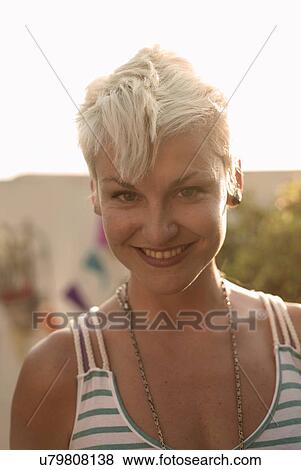 Stock Photo - Sunlit portrait of young woman with cropped blond hair. Fotosearch