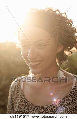 Sunlit portrait of young woman with curly hair wearing hairband View Large Photo Image Stock Photo - Sunlit portrait of young woman with curly hair wearing hairband. Fotosearch