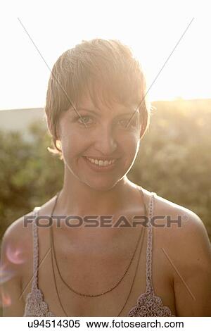 Stock Photography - Sunlit portrait of young woman with short brown hair. Fotosearch