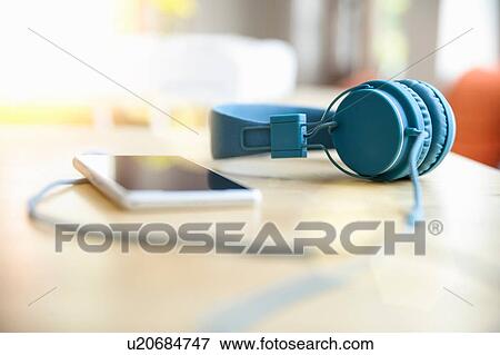 Surface level view of blue headphones attached to smartphone on table View Large Photo Image Stock Photo - Surface level view of blue headphones attached to smartphone on table. Fotosearch