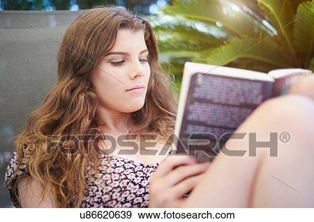 Teenage girl sitting on sun lounger reading book View Large Photo Image Stock Photo - Teenage girl sitting on sun lounger reading book. Fotosearch