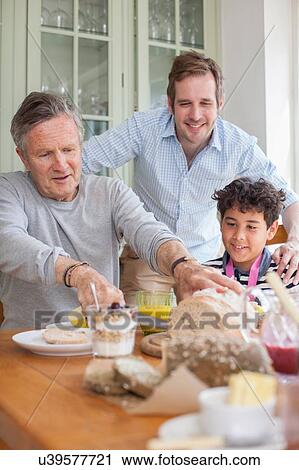 Stock Image - Three generation family eating meal. Fotosearch