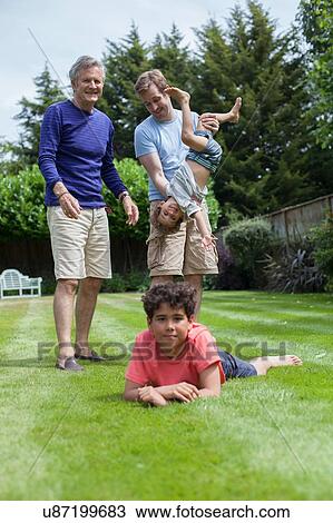 Stock Image - Three generation family fooling around in garden. Fotosearch