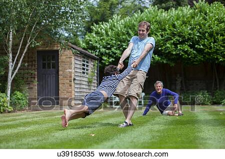 Stock Photography - Three generation family fooling around in garden. Fotosearch