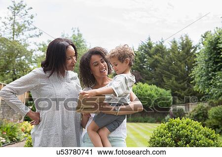 Stock Image - "Three generation family, mother showing book to son". Fotosearch