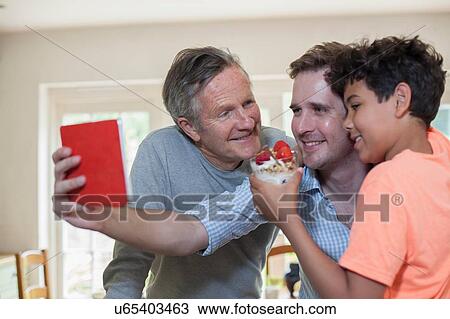 Stock Image - "Three generation family, taking self portrait, using digital tablet". Fotosearch