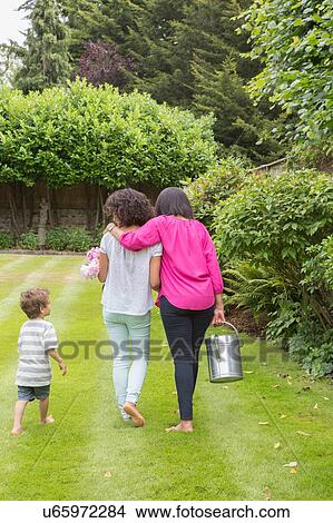 "Three generation family, walking together in garden, rear view" View Large Photo Image Picture - "Three generation family, walking together in garden, rear view". Fotosearch