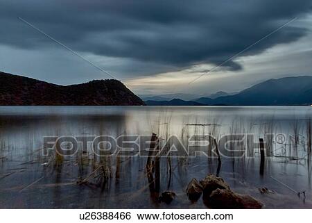 Stock Photograph - "Tranquil view of silhouetted reeds on Lugu Lake at dusk, Yunnan, China". Fotosearch