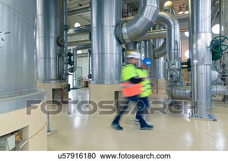 Stock Image - Two engineers walking through engine room in geothermal power station. Fotosearch