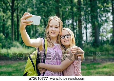 "Two young girls, outdoors, taking self portrait with smartphone" View Large Photo Image Stock Photo - "Two young girls, outdoors, taking self portrait with smartphone". Fotosearch