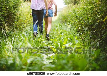 "Two young girls, walking through meadow, rear view, low section" View Large Photo Image Stock Photograph - "Two young girls, walking through meadow, rear view, low section". Fotosearch