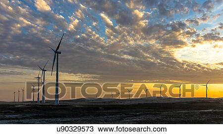 Stock Image - Wind turbines in a row on wind farm against dramatic sky. Fotosearch