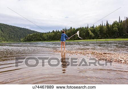 "Young boy standing in lake, fishing with fishing net, rear view" View Large Photo Image Stock Photo - "Young boy standing in lake, fishing with fishing net, rear view". Fotosearch