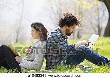 Young couple back to back on picnic blanket using digital tablet and reading View Large Photo Image Stock Image - Young couple back to back on picnic blanket using digital tablet and reading. Fotosearch