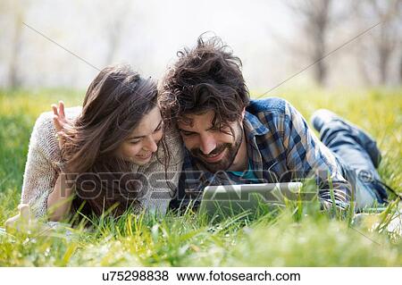 Stock Photo - Young couple on picnic blanket browsing digital tablet. Fotosearch