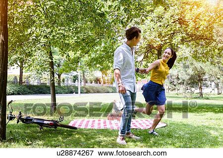 Young couple on picnic frolicking in park View Large Photo Image Stock Photo - Young couple on picnic frolicking in park. Fotosearch