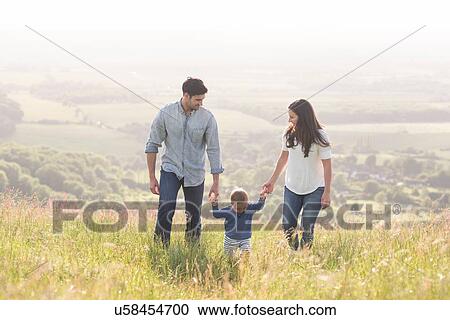 "Young family walking in field, hand in hand" View Large Photo Image Stock Image - "Young family walking in field, hand in hand". Fotosearch