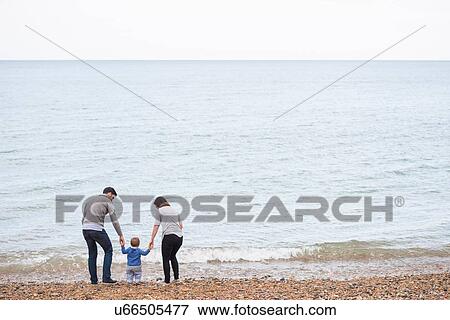 "Young family walking on pebble beach, rear view" View Large Photo Image Stock Photo - "Young family walking on pebble beach, rear view". Fotosearch