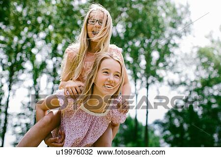 Young girl giving sister a piggyback ride View Large Photo Image Stock Image - Young girl giving sister a piggyback ride. Fotosearch