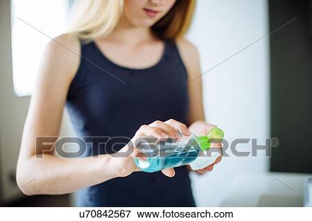 Stock Photo - "Young girl in bathroom, applying cleanser to cotton wool". Fotosearch