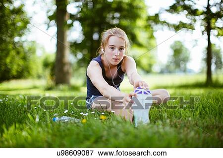 Stock Photo - "Young girl in park, doing stretches on grass". Fotosearch