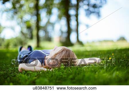 "Young girl in park, lying on grass, relaxaing" View Large Photo Image Stock Image - "Young girl in park, lying on grass, relaxaing". Fotosearch