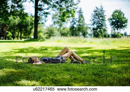 Stock Photography - "Young girl in park, lying on grass, relaxing". Fotosearch