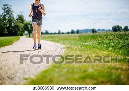 Stock Image - "Young girl in park, running on pathway, low section". Fotosearch