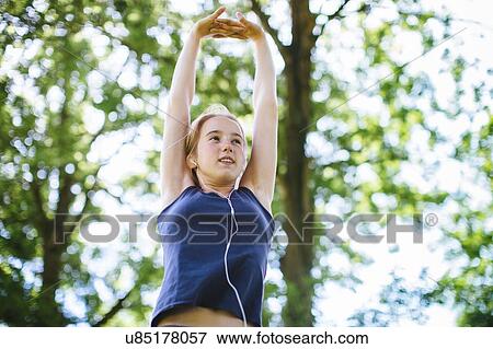 "Young girl in park, stretching arms, low angle view" View Large Photo Image Stock Photo - "Young girl in park, stretching arms, low angle view". Fotosearch
