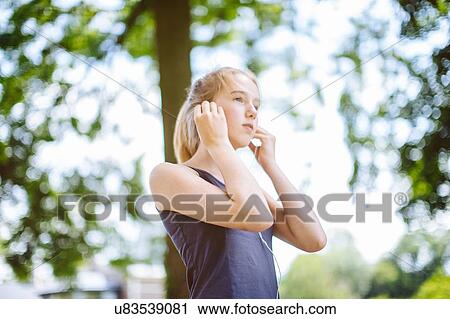 "Young girl, outdoors, putting earphones in, low angle view" View Large Photo Image Stock Image - "Young girl, outdoors, putting earphones in, low angle view". Fotosearch