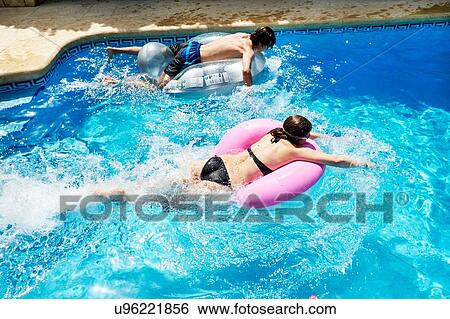 Young man and teenage sister racing on inflatables in swimming pool View Large Photo Image Stock Photograph - Young man and teenage sister racing on inflatables in swimming pool. Fotosearch