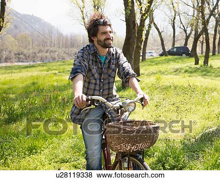 Stock Photo - Young man cycling in rural woodland. Fotosearch