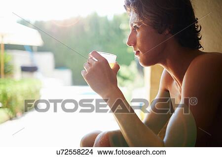 Picture - Young man drinking soft drink on patio chair. Fotosearch